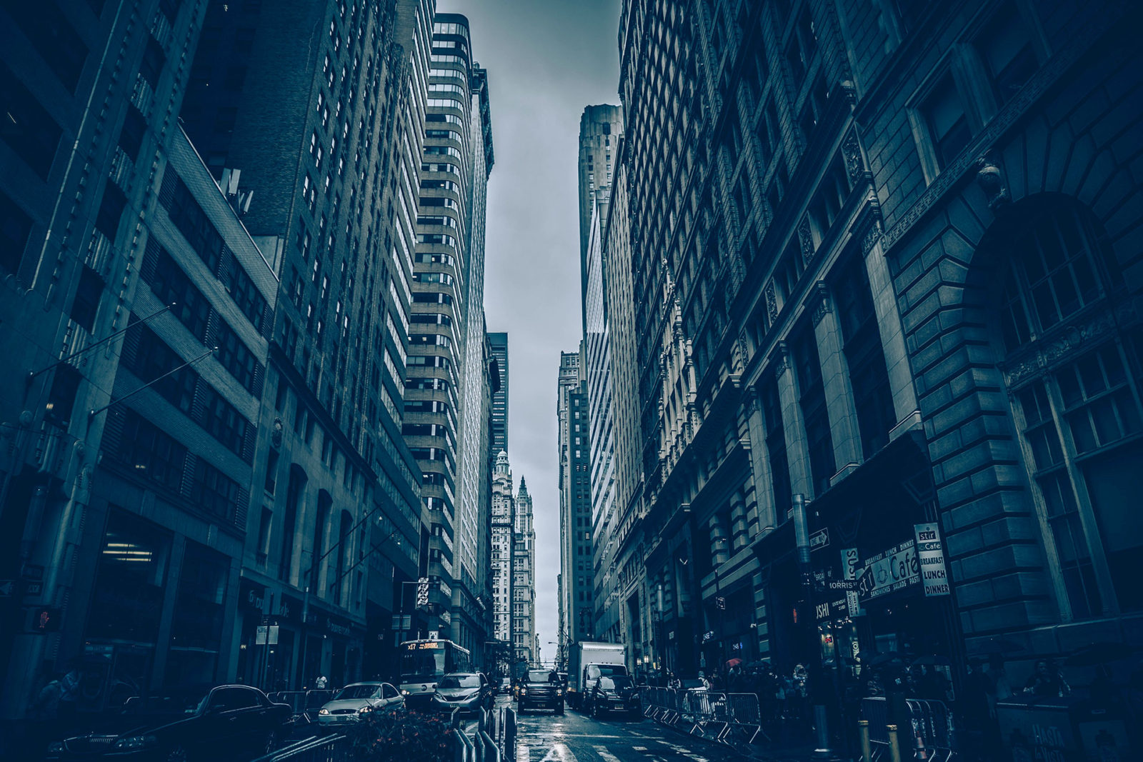 Rainy city street lined with tall skyscrapers